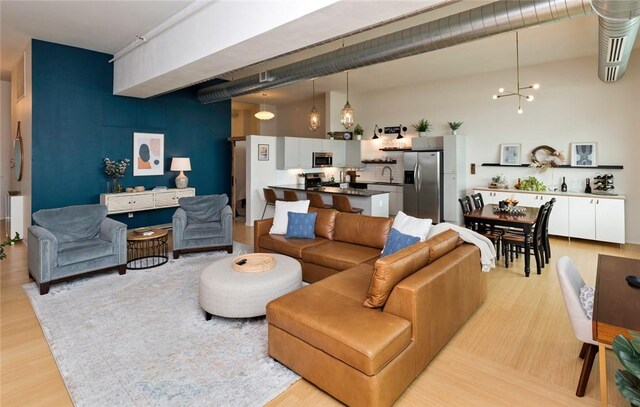 living room featuring a notable chandelier, sink, rail lighting, and light wood-type flooring