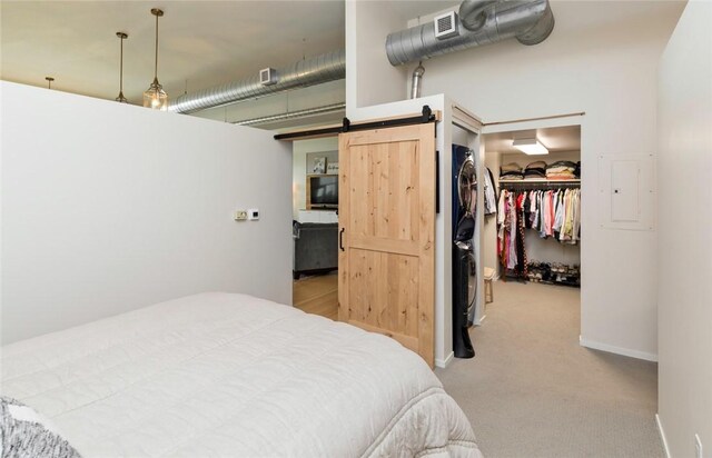 bedroom featuring a closet, a walk in closet, light carpet, a barn door, and electric panel