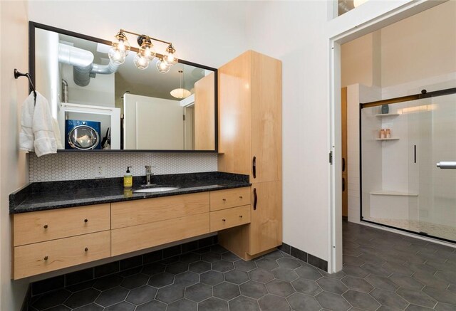 bathroom featuring a shower with shower door, vanity, tile patterned floors, and tasteful backsplash