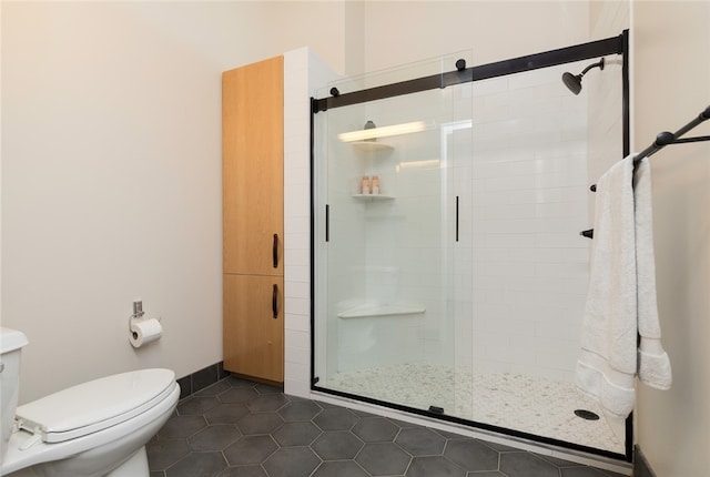 bathroom featuring tile patterned flooring, toilet, and an enclosed shower