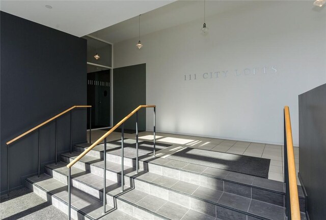 stairway with light tile patterned floors and a high ceiling