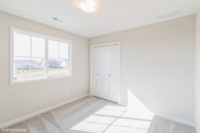 unfurnished bedroom featuring a closet and light carpet