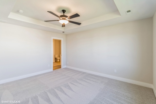 carpeted empty room with a tray ceiling and ceiling fan