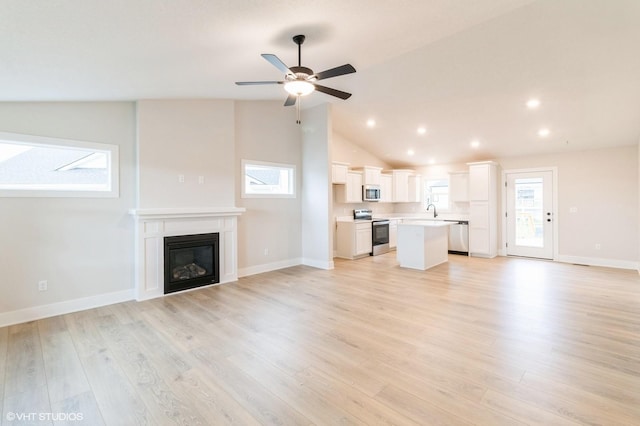 unfurnished living room featuring a sink, light wood-style flooring, and a healthy amount of sunlight