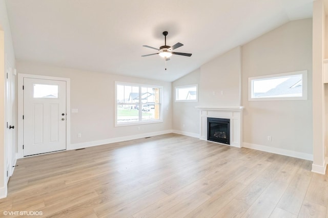 unfurnished living room with light wood-style floors, a glass covered fireplace, vaulted ceiling, and a ceiling fan