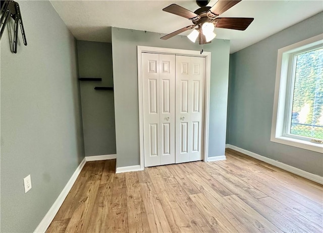 unfurnished bedroom with multiple windows, a closet, ceiling fan, and light wood-type flooring