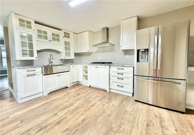 kitchen with wall chimney exhaust hood, white cabinetry, stainless steel appliances, and light stone counters