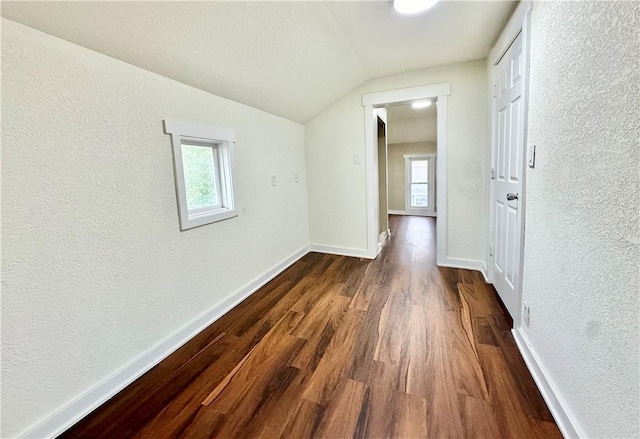 hall featuring vaulted ceiling, dark hardwood / wood-style floors, a textured ceiling, and plenty of natural light