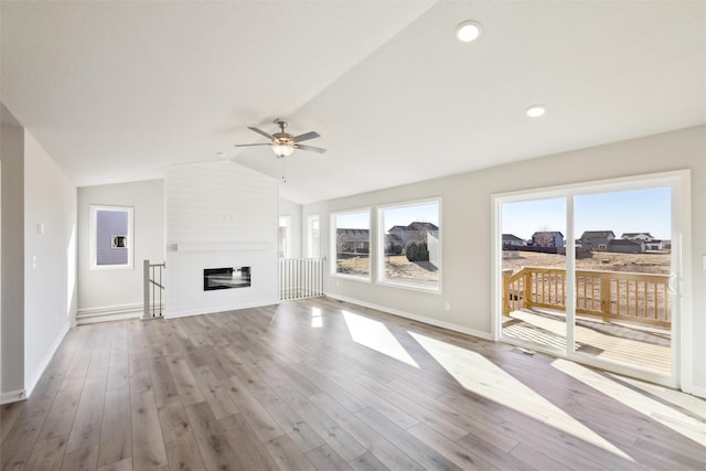 unfurnished living room featuring plenty of natural light, vaulted ceiling, and light hardwood / wood-style flooring