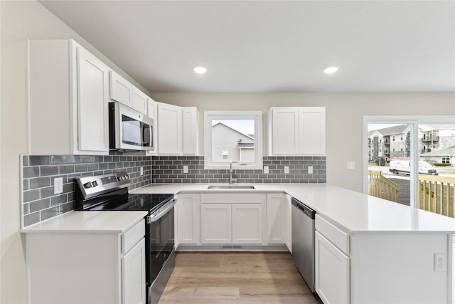 303 29th St SW, Altoona, IA 50009 - kitchen featuring appliances with stainless steel finishes, a peninsula, plenty of natural light, light wood-style floors, and recessed lighting