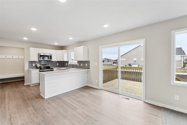 303 29th St SW, Altoona, IA 50009 - kitchen featuring appliances with stainless steel finishes, light wood-type flooring, a peninsula, white cabinets, and recessed lighting