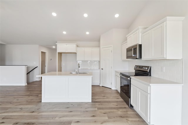 kitchen with white cabinetry, black range with electric stovetop, a kitchen island with sink, and light wood-type flooring