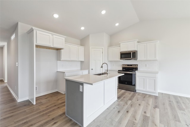 kitchen featuring appliances with stainless steel finishes, a kitchen island with sink, sink, white cabinets, and lofted ceiling