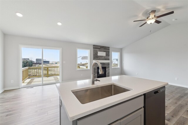 kitchen featuring sink, black dishwasher, an island with sink, light hardwood / wood-style floors, and lofted ceiling