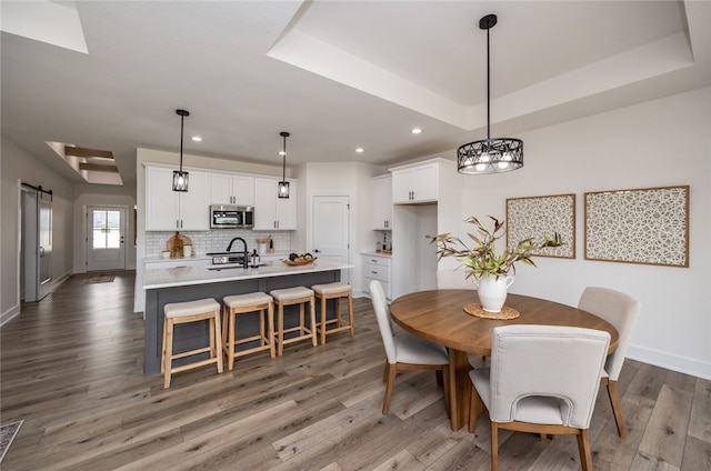 dining room featuring sink, a barn door, hardwood / wood-style flooring, and a raised ceiling