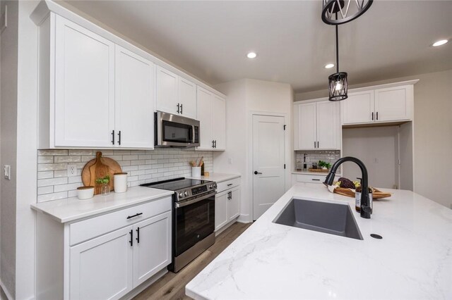 kitchen with decorative backsplash, stainless steel appliances, light stone countertops, and sink