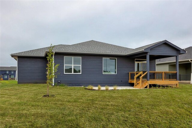 rear view of house with a wooden deck and a lawn