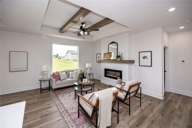 living room with ceiling fan, a tray ceiling, beamed ceiling, and hardwood / wood-style flooring