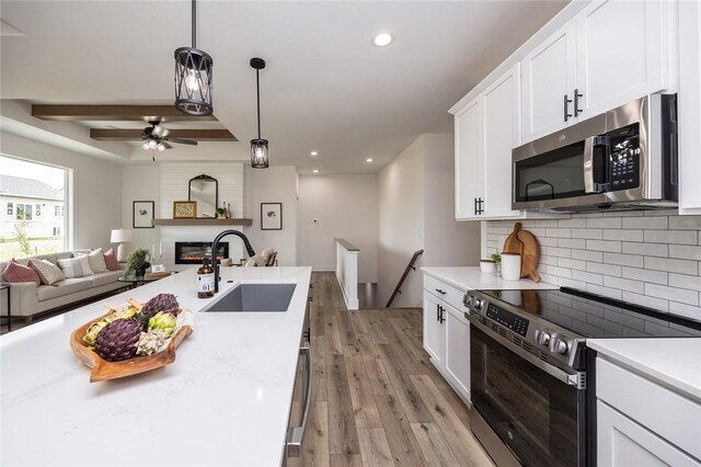 kitchen with white cabinetry, tasteful backsplash, stainless steel appliances, light hardwood / wood-style floors, and sink