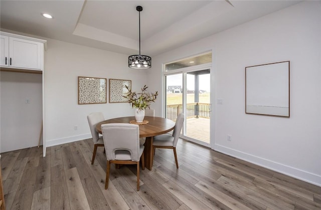 dining room featuring hardwood / wood-style flooring, a raised ceiling, and a notable chandelier