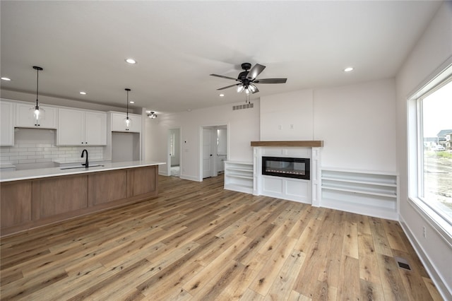 kitchen featuring a healthy amount of sunlight, tasteful backsplash, white cabinets, and light hardwood / wood-style floors