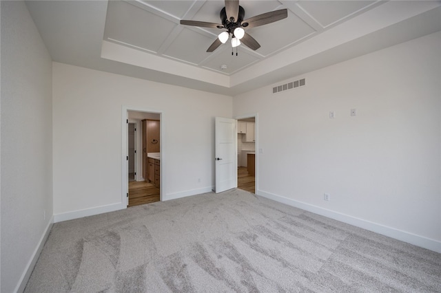 unfurnished bedroom with light wood-type flooring, connected bathroom, a tray ceiling, ceiling fan, and coffered ceiling