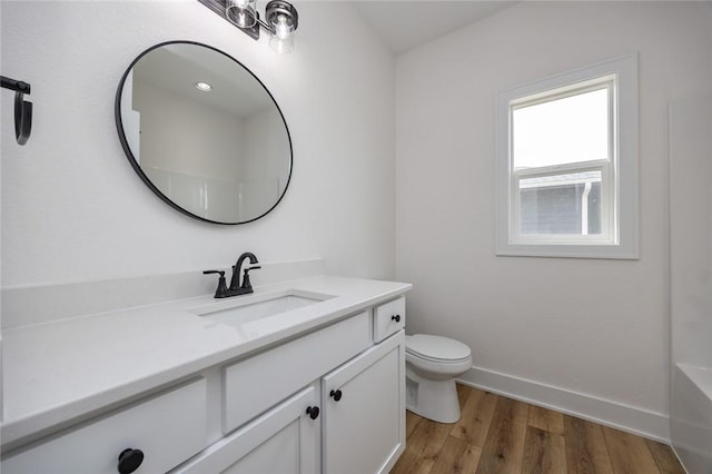 bathroom with hardwood / wood-style flooring, a healthy amount of sunlight, toilet, and vanity