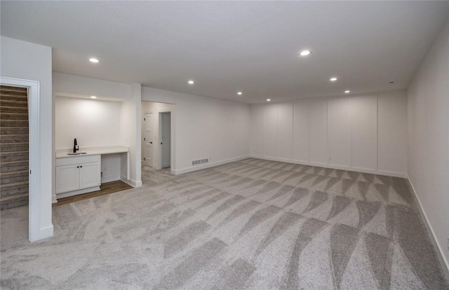 basement with sink and light colored carpet