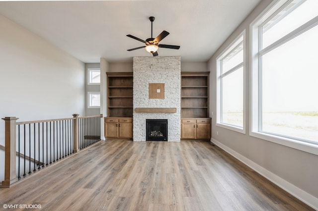 unfurnished living room with a fireplace, light wood-type flooring, and ceiling fan