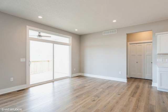 spare room featuring a textured ceiling, light wood-type flooring, and ceiling fan