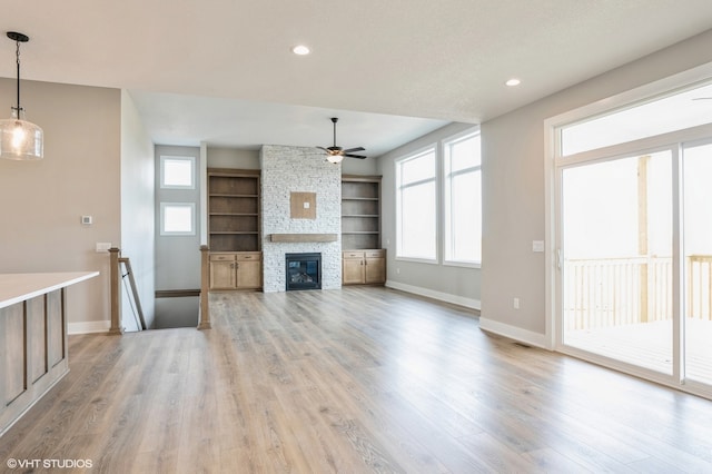 unfurnished living room featuring light hardwood / wood-style flooring, a fireplace, and ceiling fan