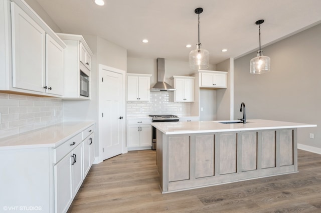 kitchen with wall chimney exhaust hood, white cabinetry, and stainless steel stove