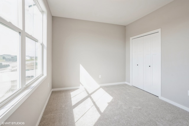 unfurnished bedroom with a closet and light colored carpet