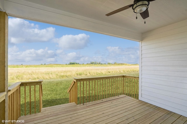 wooden deck featuring a yard, ceiling fan, and a rural view