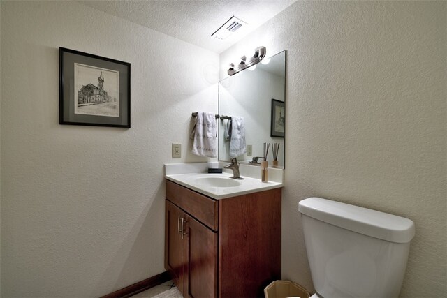 bathroom with toilet, vanity, and a textured ceiling