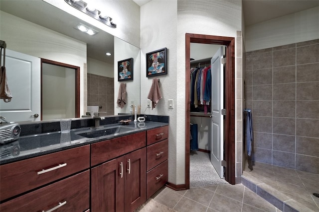 bathroom with tiled shower, tile patterned floors, and vanity