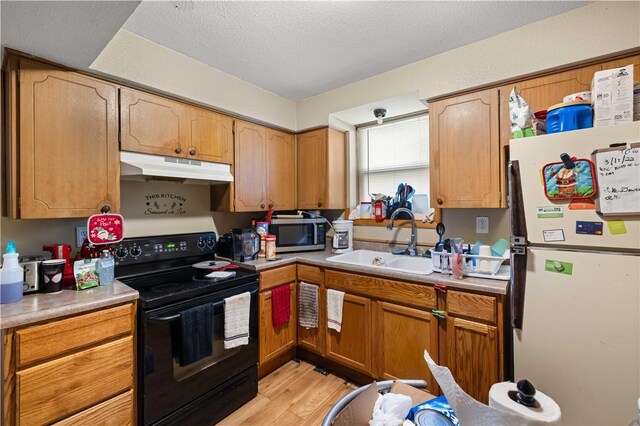 kitchen featuring a textured ceiling, light hardwood / wood-style floors, black range with electric cooktop, white refrigerator, and sink