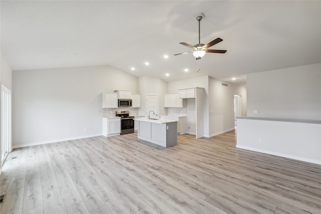 kitchen with white cabinetry, stainless steel appliances, an island with sink, vaulted ceiling, and light wood-type flooring