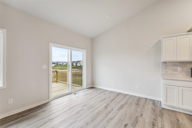 unfurnished dining area featuring light hardwood / wood-style floors and lofted ceiling