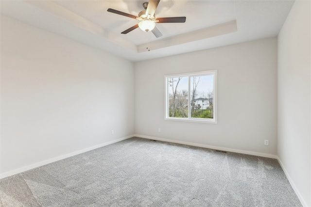 unfurnished room with carpet floors, a tray ceiling, and ceiling fan