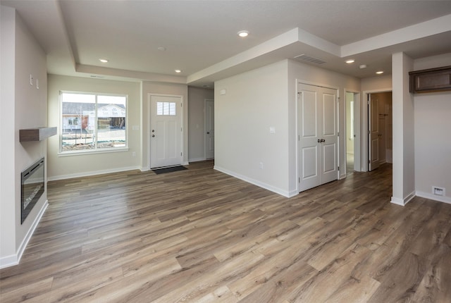 unfurnished living room with a tray ceiling and hardwood / wood-style flooring