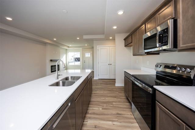 kitchen with stainless steel appliances, light hardwood / wood-style floors, sink, and dark brown cabinets