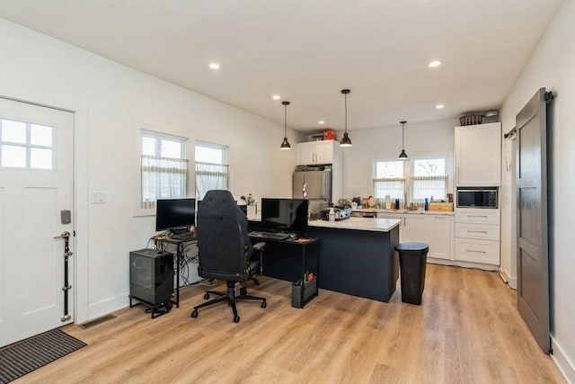 office area with a wealth of natural light and light hardwood / wood-style flooring