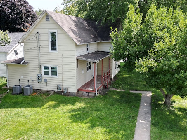 rear view of property featuring cooling unit and a yard