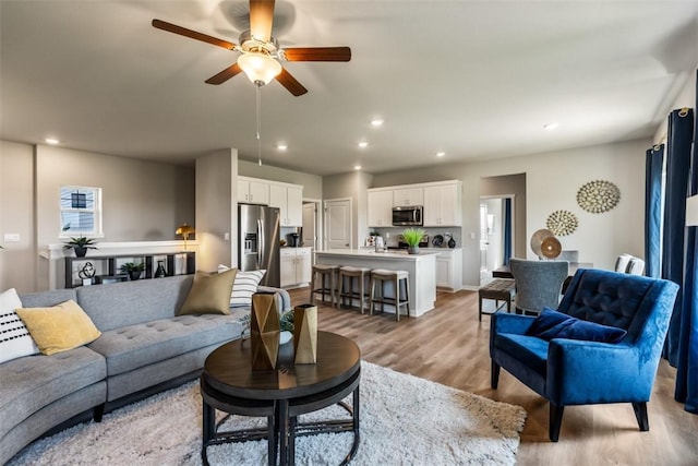 living room featuring ceiling fan and light hardwood / wood-style flooring