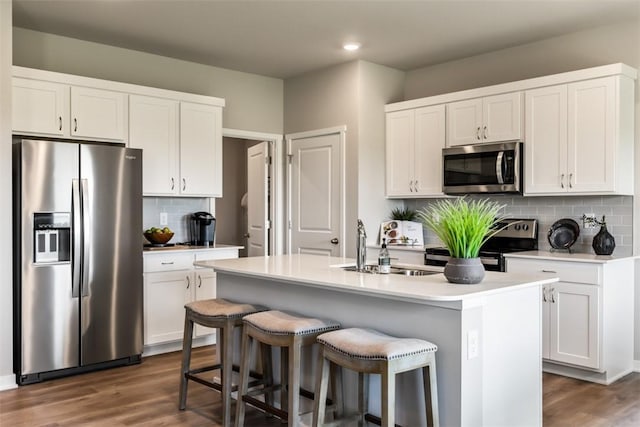 kitchen with stainless steel appliances, sink, a center island with sink, and white cabinets