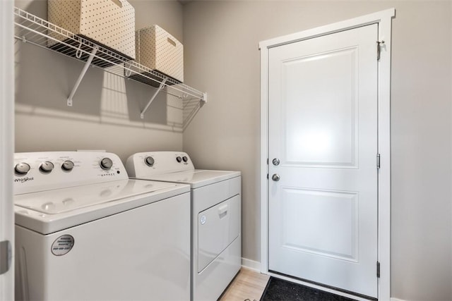 washroom with light hardwood / wood-style floors and washer and dryer