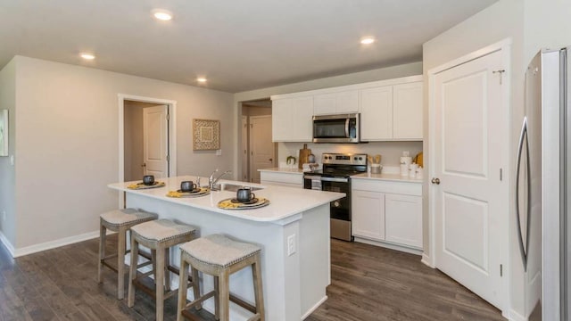 kitchen featuring appliances with stainless steel finishes, white cabinetry, an island with sink, sink, and dark wood-type flooring