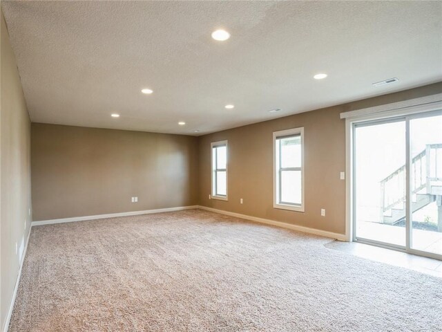 empty room with light carpet and a textured ceiling