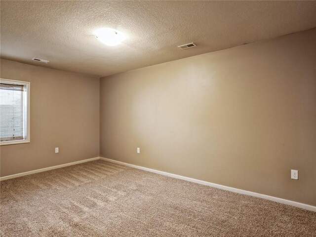 carpeted empty room featuring a textured ceiling